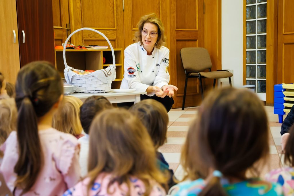 Chef Elena Pădurariu, cu un coș de fructe și legume, vorbind copiilor de Ziua Mondială a Alimentației