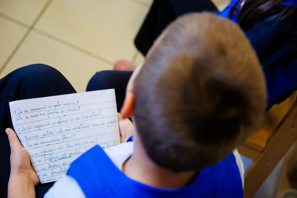 Un copil, fotografiat din spate, cu foaia de întrebări despre alimente scrisă de mână